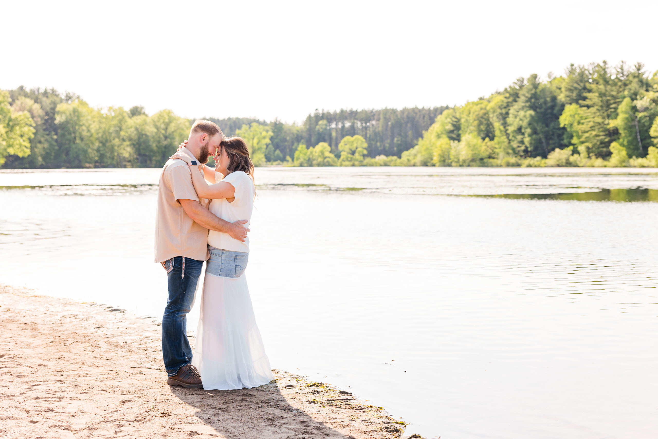 Engaged couple standing on the beach at sunset.